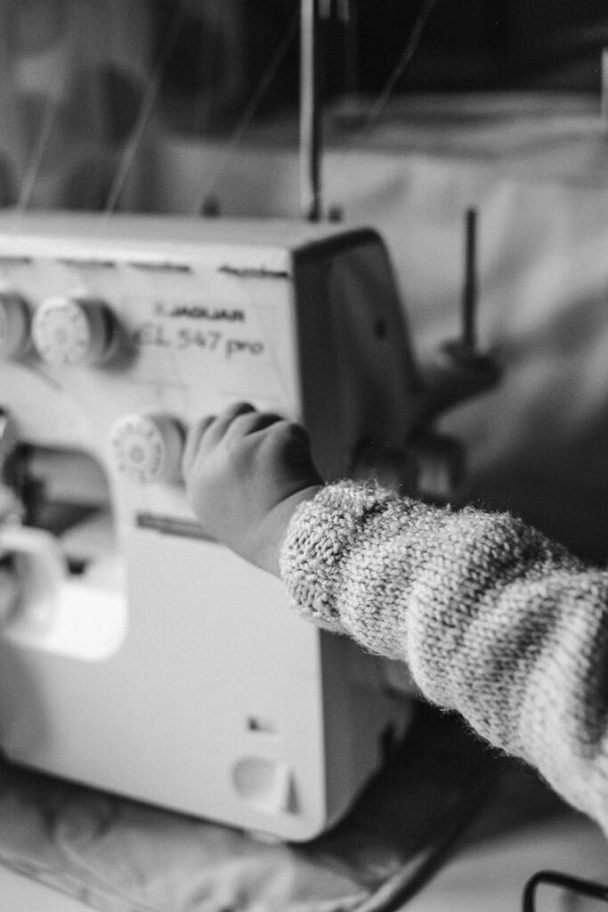 a child holding the knob of an electric sewing machine